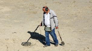 A metal detectorist on a beach